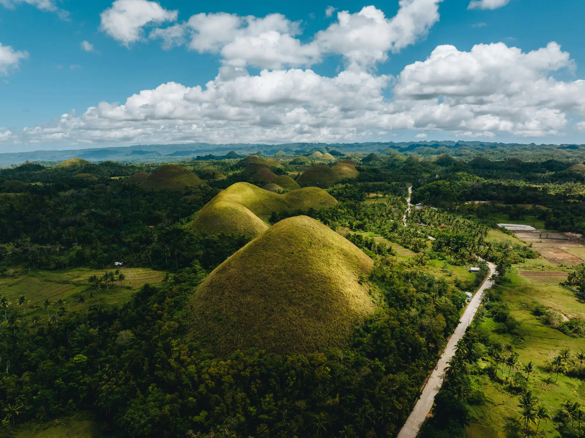 Aerial view of the Chocolate Hills under a wide blue sky.